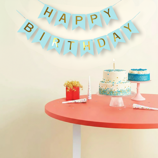 Birthday celebration setup with 'Happy Birthday' banner, cake, and party favors on a table.