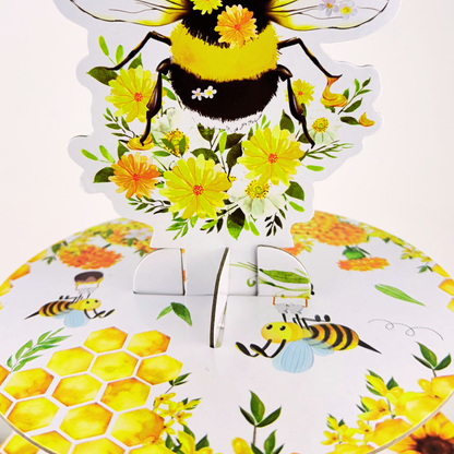 Detailed shot of the top tier assembly showing the queen bee topper inserted into the floral and bee-patterned tier.