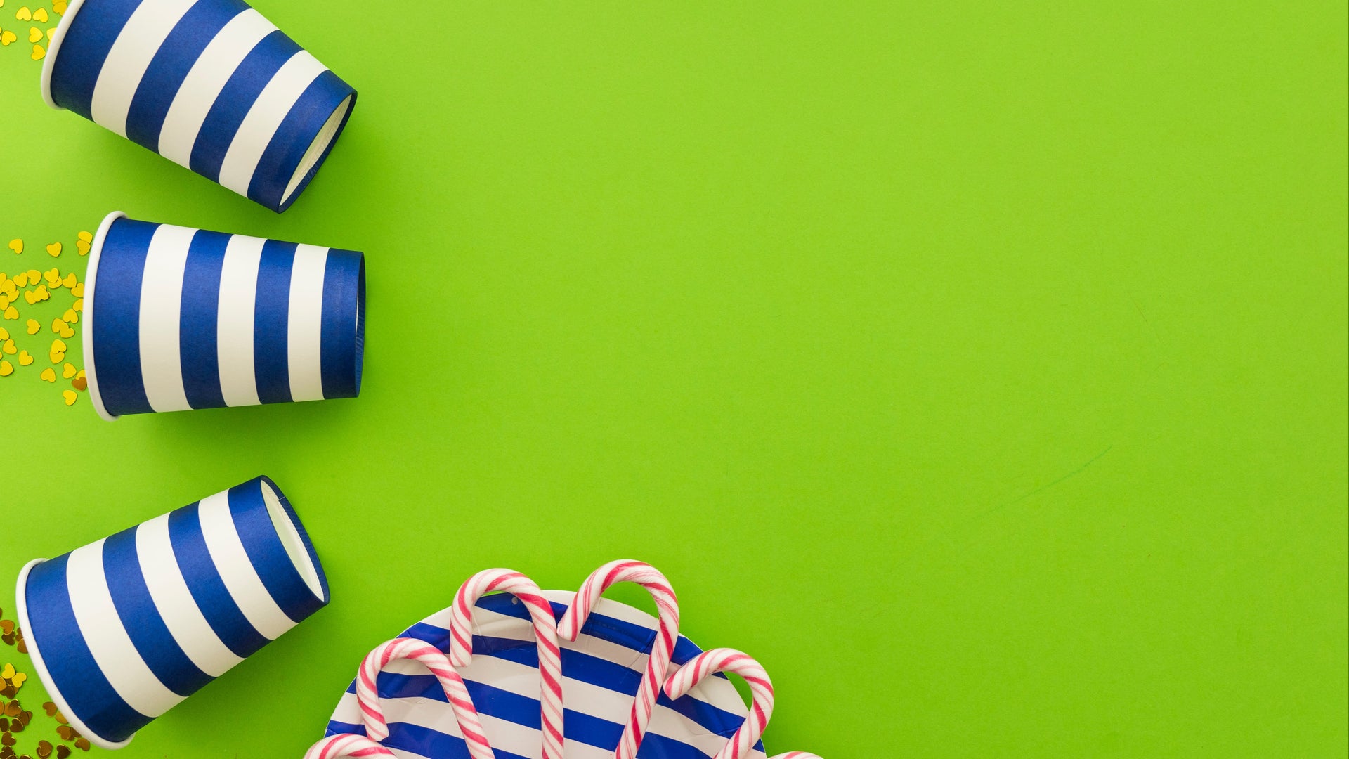 Three blue and white striped cups with candy on a green background